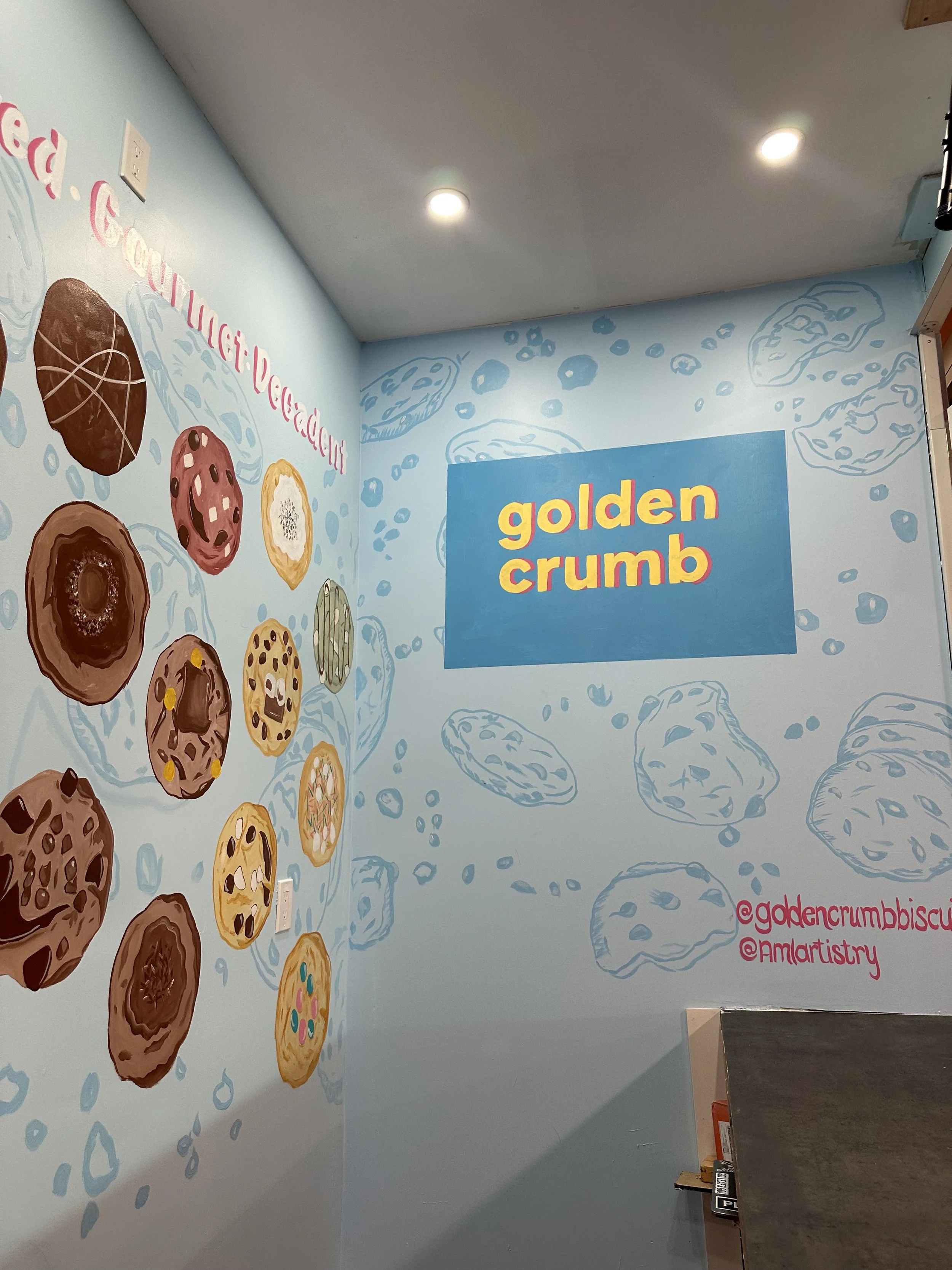 Wall with colorful cookie illustrations and a blue sign that reads 'golden crumb'.
