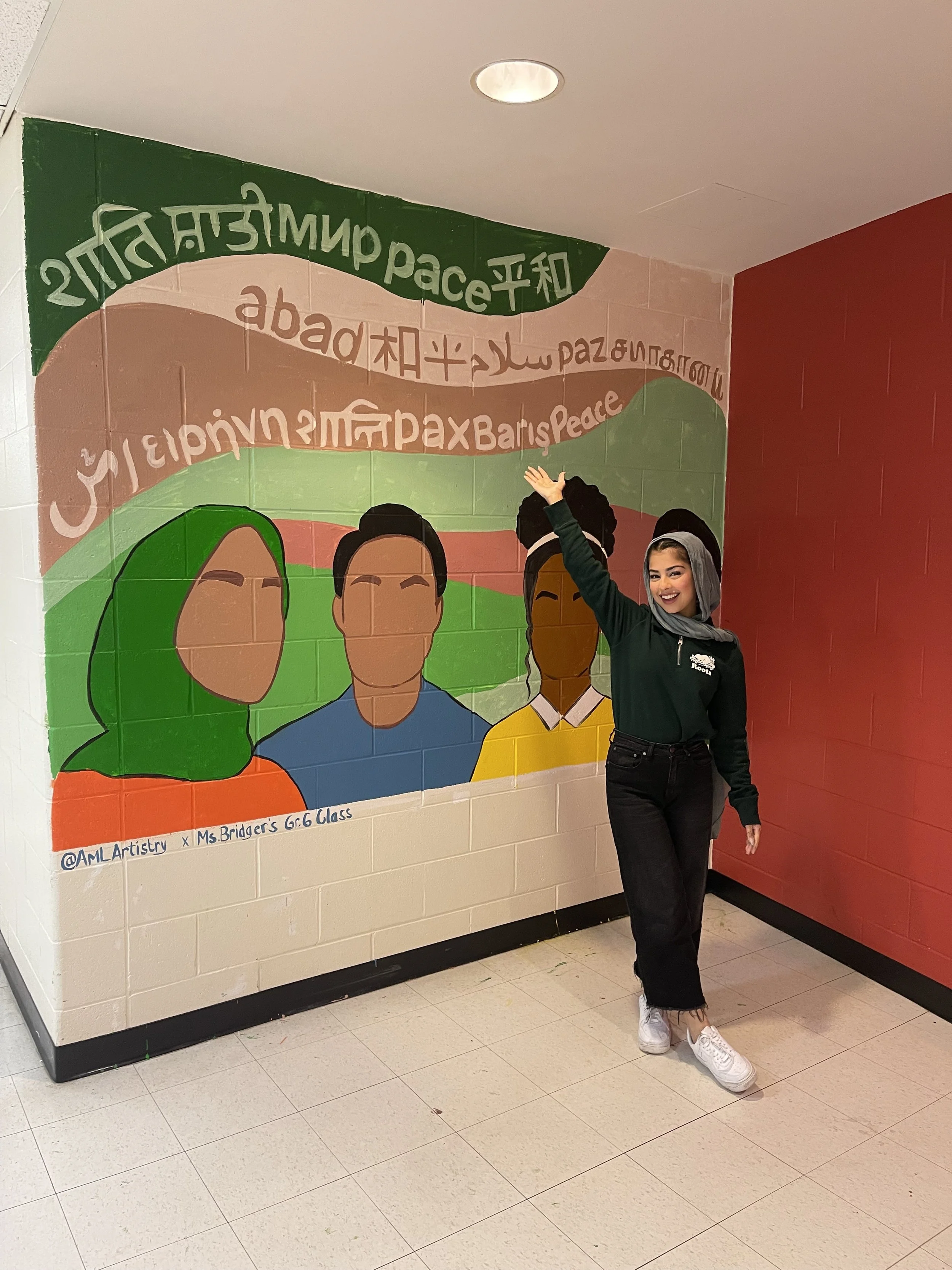 Young woman smiling and pointing at a colorful mural of diverse people and peace symbols on a school wall.